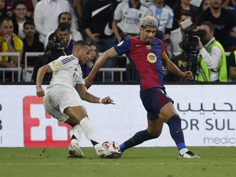 El defensa uruguayo del Barcelona Ronald Araujo (d) pelea un balón con el delantero francés del Real Madrid Kylian Mbappé durante el partido de la final de la Supercopa de España