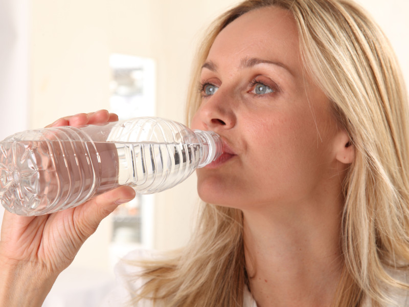 Una mujer bebe agua de una botella