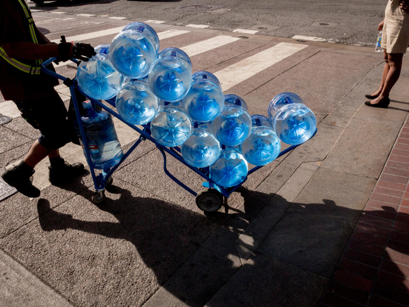 Un repartidor entrega a domicilio varios envíos de agua embotellada