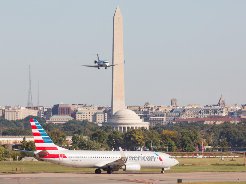 Un avión se aproxima para aterrizar mientras un avión de American Airlines se dirige a la pista con el Monumento a Washington y el Monumento a Jefferson de fondo en el Aeropuerto Nacional Reagan, al otro lado del Potomac desde Washington, durante las operaciones el 5 de octubre de 2014 en Arlington, Virginia.