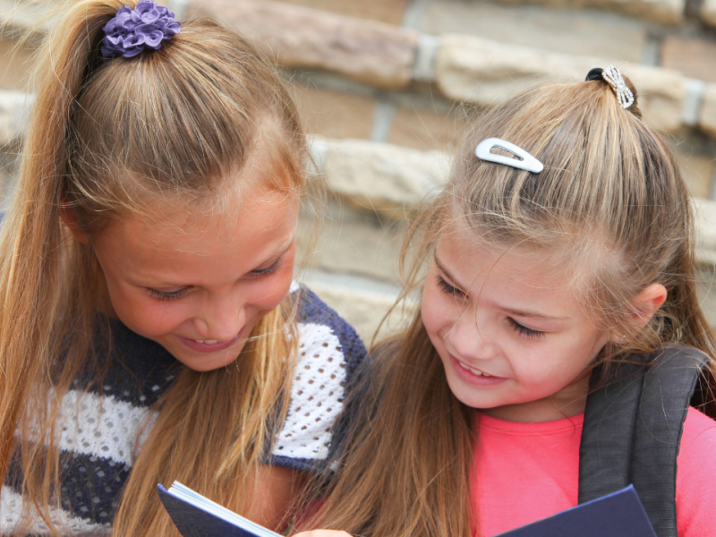 Niñas de primaria leyendo un libro