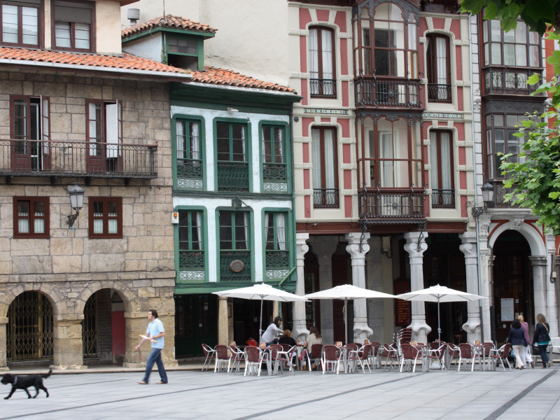 Calle de San Francisco, Avilés, Asturias, hombre y perro, terraza de café y tradicionales balcones acristalados