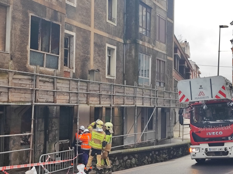 Los bomberos inspeccionan el edificio quemado en Basauri