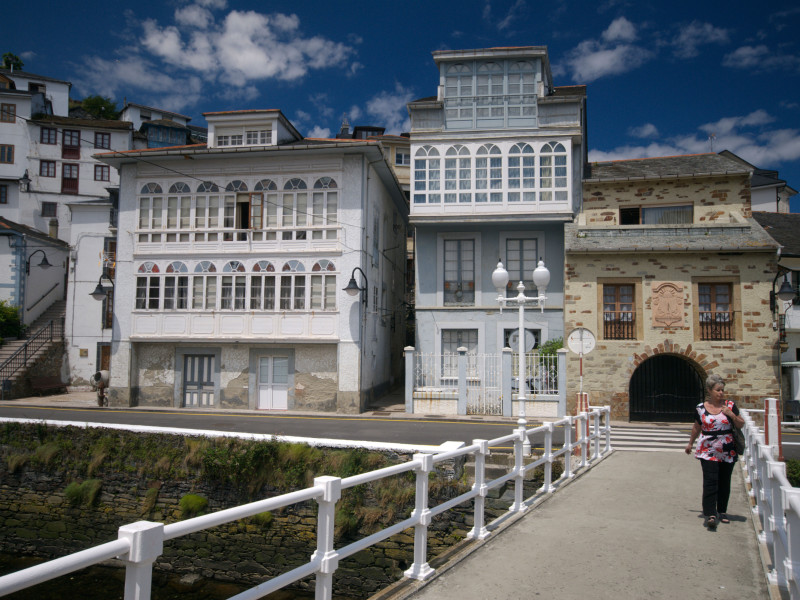 Señora cruzando el puente sobre el río en el pintoresco pueblo pesquero de Luarca en Asturias