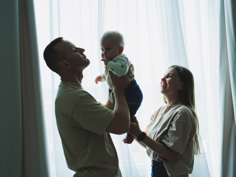 Una pareja de familia feliz con un pequeño hijo en brazos. Mamá, papá y el bebé se abrazan.