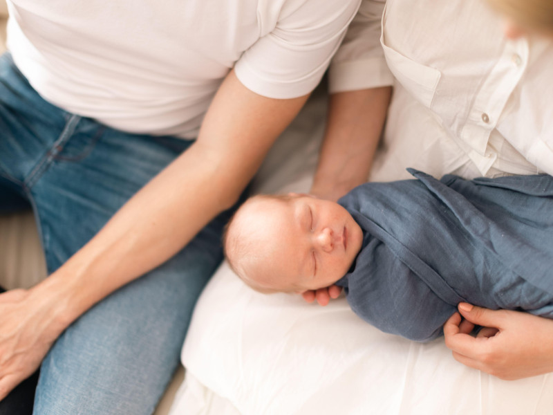 Primer plano de padres sosteniendo a su hijo recién nacido envuelto en una manta en casa