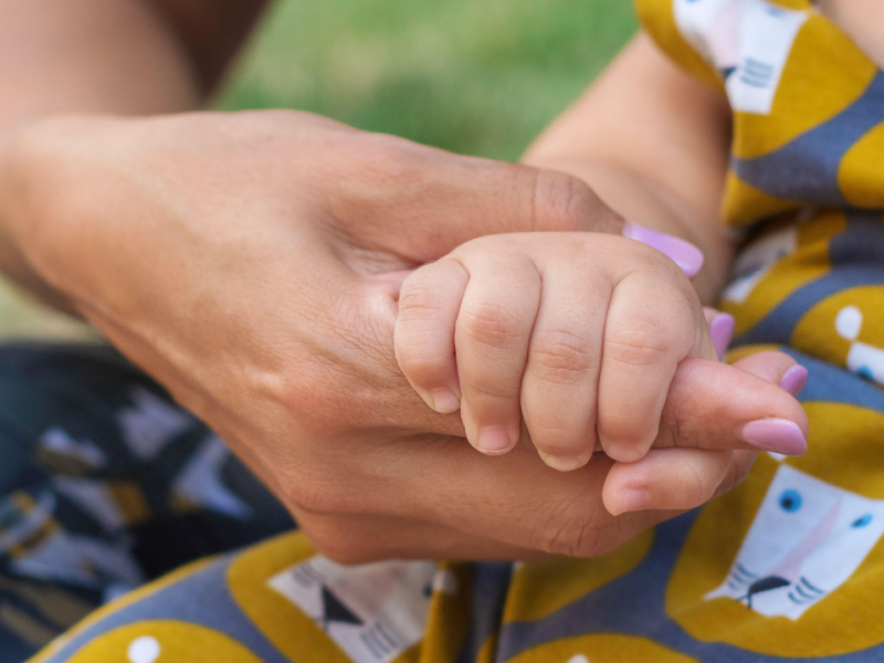 Una madre sujetando la mano de su bebe