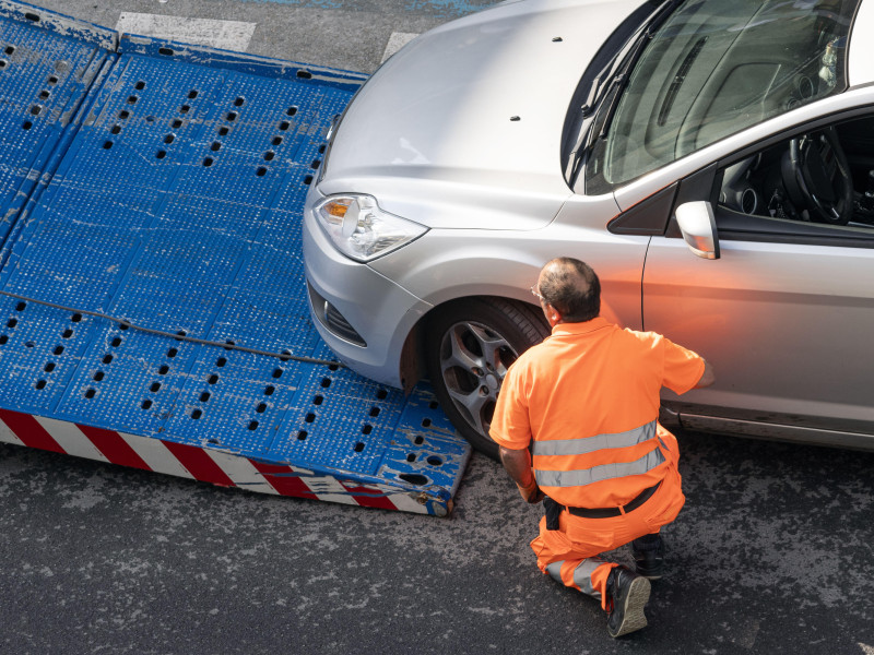 Trabajadora de asistencia en carretera levantando un coche en una grúa