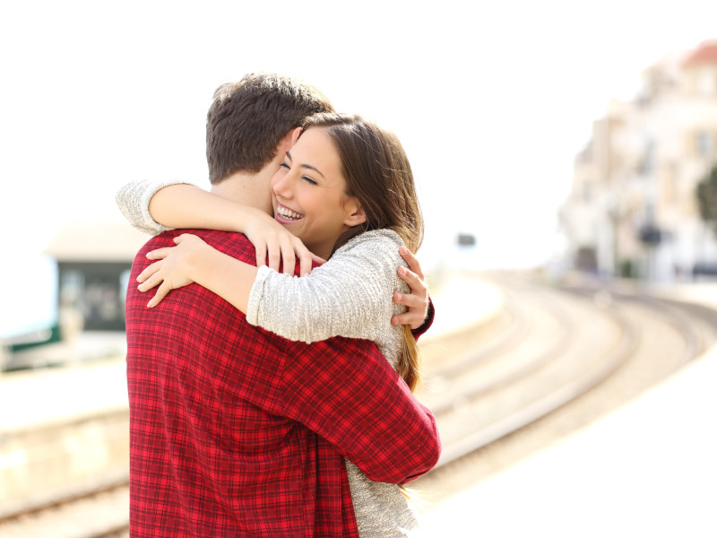 Feliz pareja abrazándose en una estación de tren después de la llegada