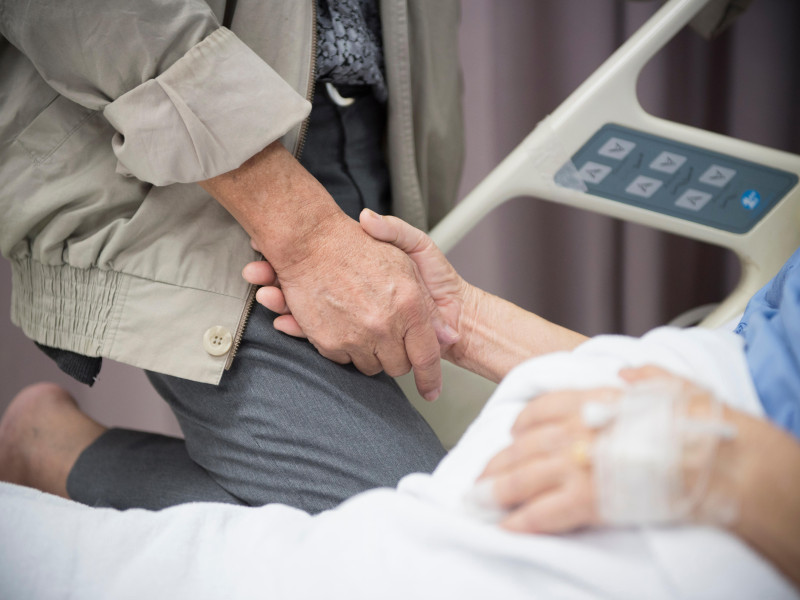 Un hombre mayor sujeta la mano de una mujer en un hospital