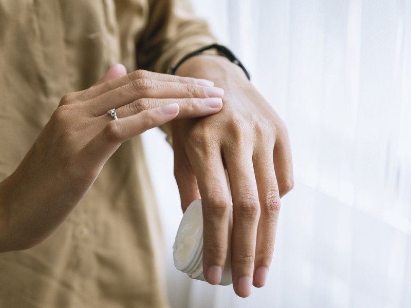 Una mujer se echa crema en una mano