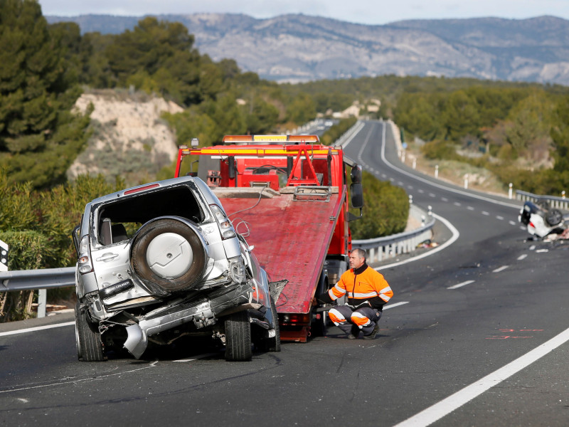 Un operario retira en una grúa uno los vehículos implicados en un accidente en el que han fallecido dos personas y otras dos han resultado heridas, tras una colisión frontal causada por un turismo que circulaba en sentido contrario por la A-7 a la altura de la localidad alicantina de Tibi.