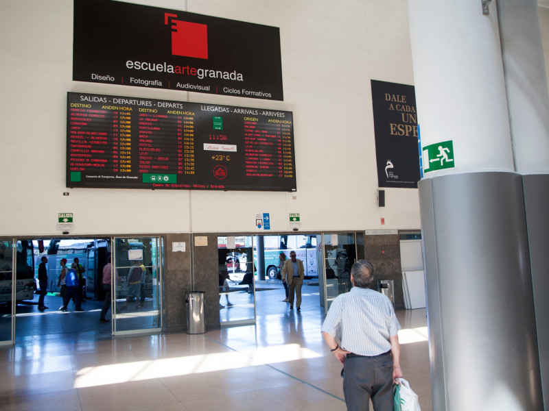 Hombre mirando el panel informativo sobre llegadas y salidas de autobuses, estación de autobuses de Granada