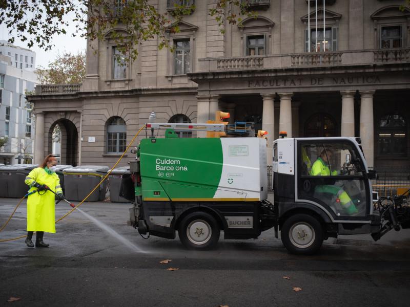 (Una trabajadora de la limpieza riega una calle en Barcelona
