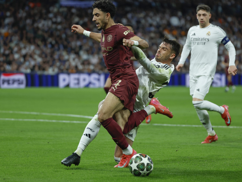 El defensa del Real Madrid Raúl Asencio (d) lucha con Omar Marmoush (i), del Manchester, durante el partido de vuelta de la eliminatoria previa a los octavos de final de la Liga de Campeones que Real Madrid y Manchester City disputan hoy miércoles en el estadio Santiago Bernabéu