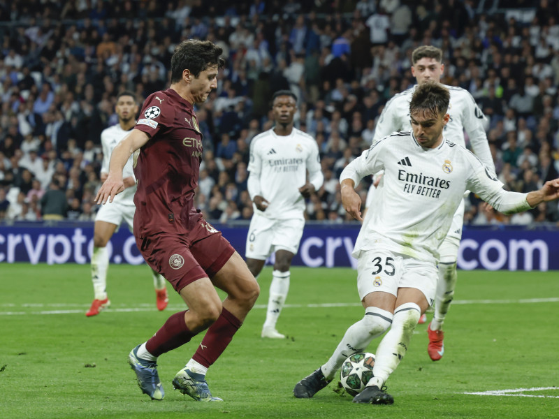 El defensa uzbeko del Manchester City Abdukodir Khusanov (i) lucha con Raúl Asencio, del Real Madrid, durante el partido de vuelta de la eliminatoria previa a los octavos de final de la Liga de Campeones que Real Madrid y Manchester City disputan hoy miércoles en el estadio Santiago Bernabéu