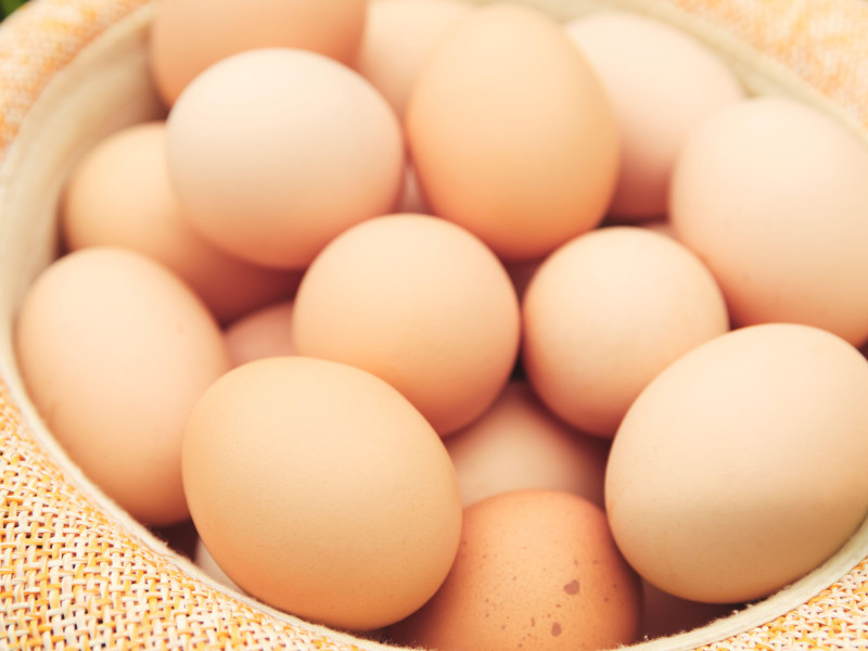 Huevos de gallina en una canasta de madera sobre un suelo verde natural en un día nublado