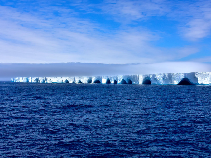 Iceberg azul flotando en la Antártida en un día soleado con cielo azul