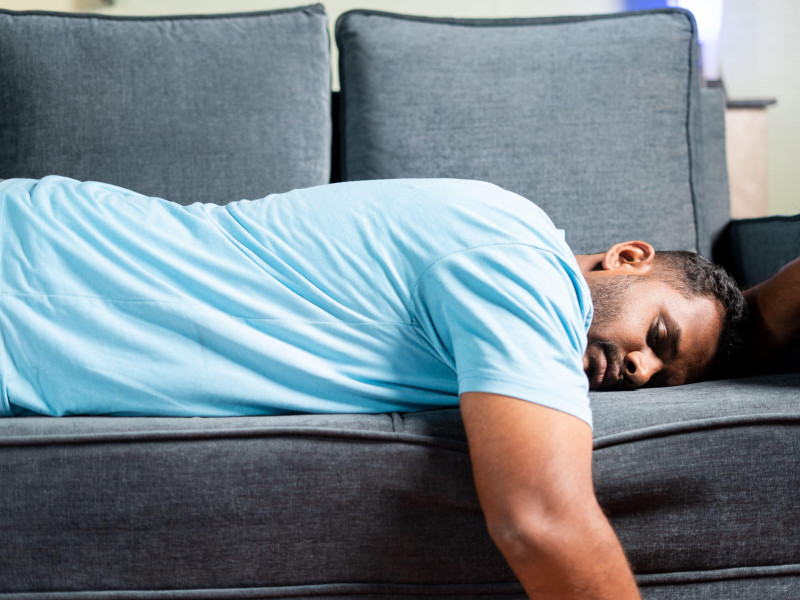 Hombre gordo y cansado durmiendo en un sofá en casa: concepto que muestra descanso, vacaciones de fin de semana y agotamiento debido al exceso de trabajo