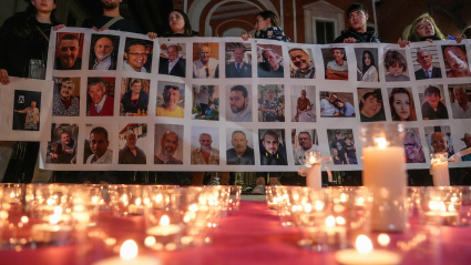 Varias personas sostienen un cartel con imágenes de algunos fallecidos, durante una conmemoración por las víctimas de la DANA en Valencia