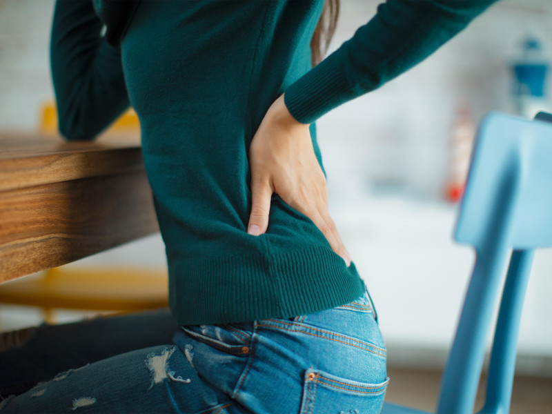 Mujer con dolor de espalda sentada en una silla o en la oficina