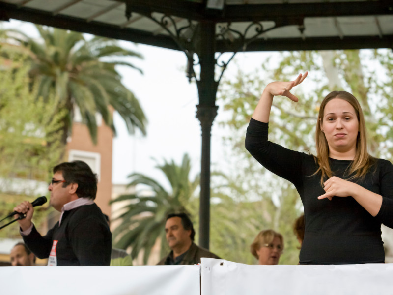 Badajoz, España - 29 de marzo de 2012: una intérprete de lengua de signos hace un gesto durante una reunión de protesta contra los recortes de austeridad