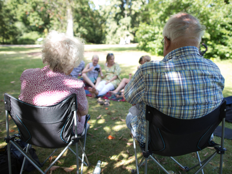 Abuelos, jubilados, bajo el sol, observando a las generaciones más jóvenes de su familia.