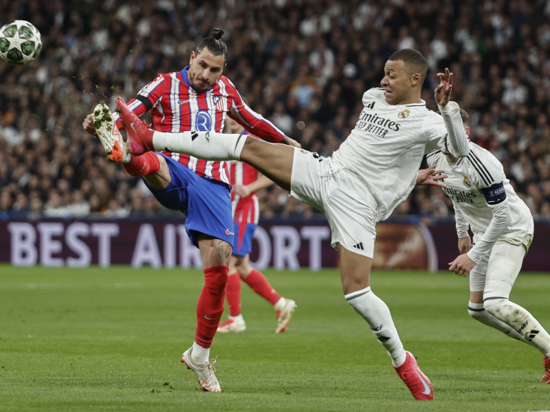 El defensa del Atlético de Madrid José Giménez (i) lucha con el francés Kylian Mbappé, del Real Madrid, durante el encuentro correspondiente a la ida de los octavos de final de la Liga de Campeones que Real Madrid y Atlético de Madrid disputan hoy martes en el estadio Santiago Bernabéu, en Madrid