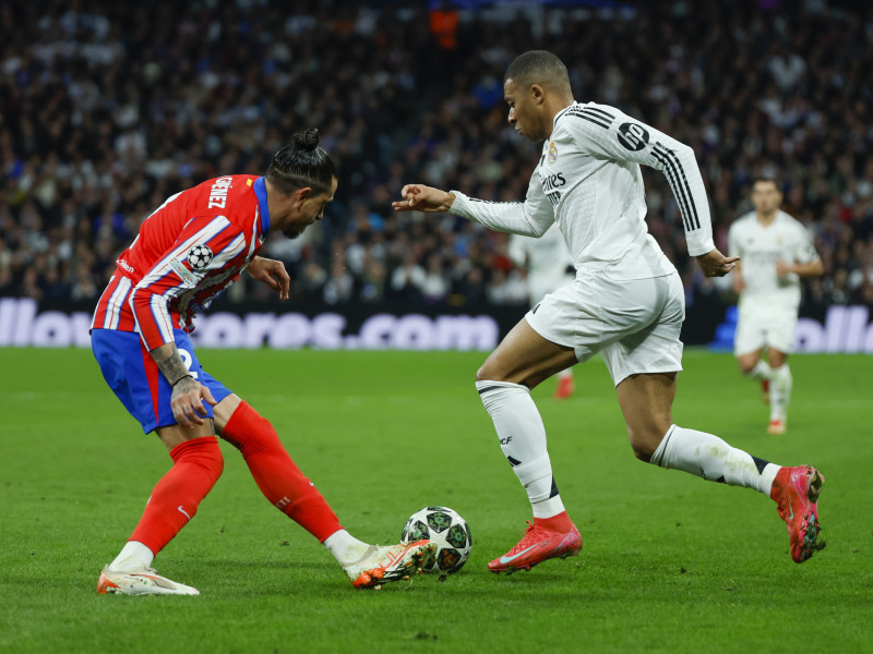 El delantero francés del Real Madrid, Kylian Mbappé (d), se lleva el balón ante el defensa uruguayo del Atlético de Madrid, José María Giménez, durante el encuentro correspondiente a la ida de los octavos de final de la Liga de Campeones que Real Madrid y Atlético de Madrid disputan hoy martes en el estadio Santiago Bernabéu, en Madrid