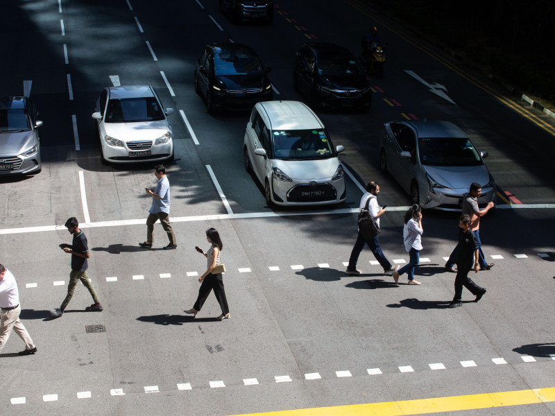 Peatones cruzan la calle mirando sus móviles