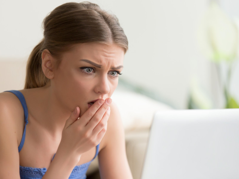 Mujer mirando la pantalla de la computadora portátil con miedo