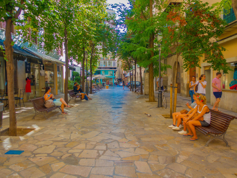 Personas sentadas en sillas públicas mientras otros turistas siguen caminando por el Boulevard Born en Palma de Mallorca