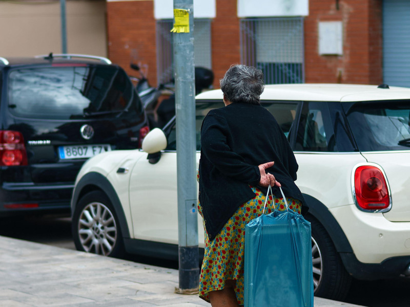 Mujer mayor que lleva una pintura de la Virgen en una bolsa