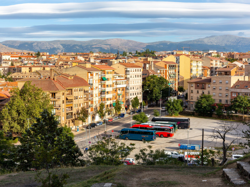 Paisaje urbano de Segovia con un barrio residencial con estrechas calles de piedra, arquitectura medieval y aparcamiento para autobuses turísticos