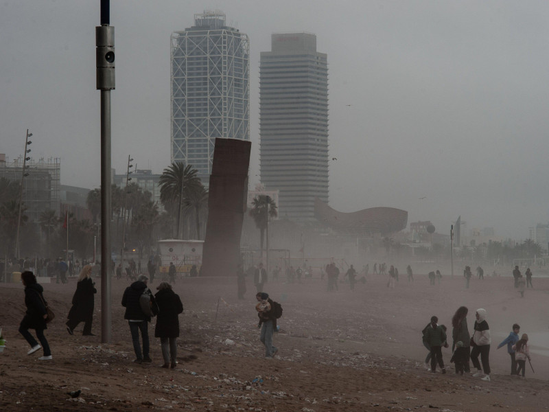 La gente camina por la playa de la Barceloneta en Barcelona en medio de la bruma