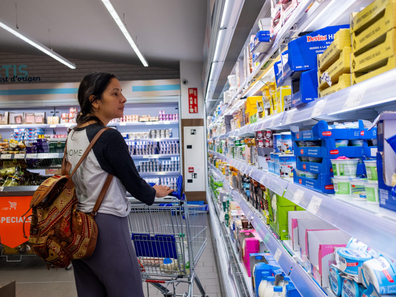 Una mujer es vista recogiendo productos del refrigerador de un supermercado Aldi mientras hace compras.