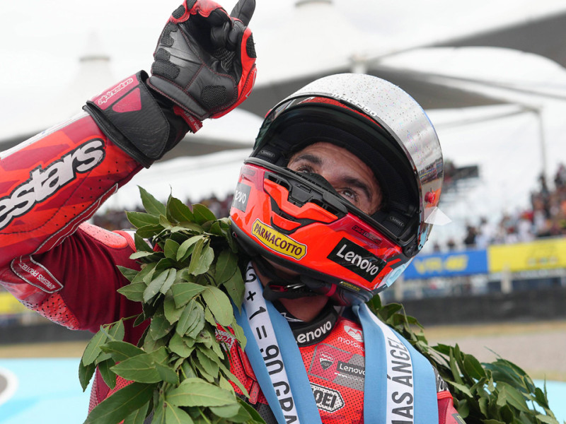 Marc Márquez, con una corona conmemorativa en memoria de Ángel Nieto, con el dedo señalando al cielo