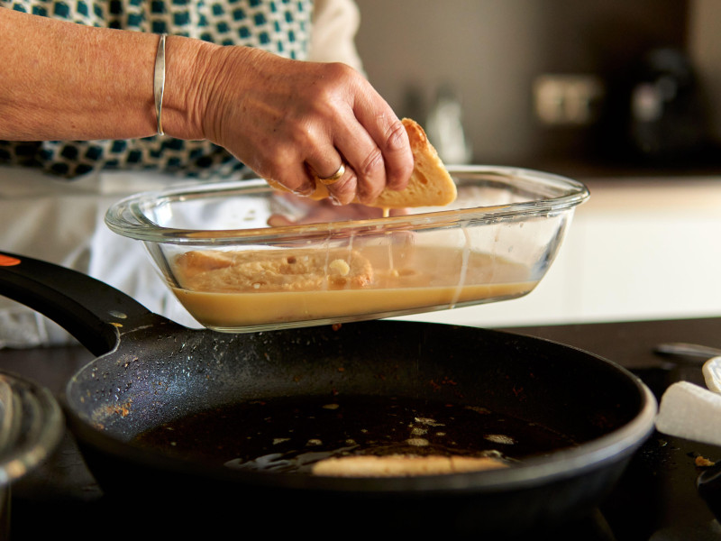 Primer plano de las manos de una abuela friendo torrijas españolas