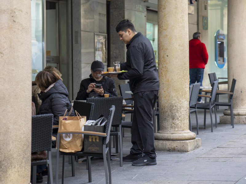 Un camarero sirve un café en la terraza de una cafetería en Teruel