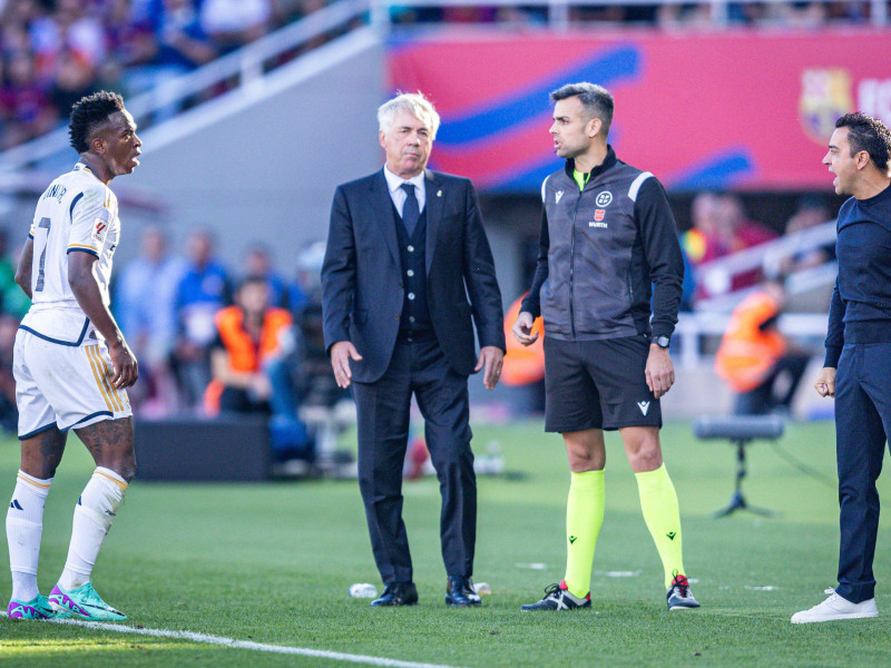 Vinicius Junior (Real Madrid) (I) discute con Xavi Hernández (Barcelona) (D) con Carlo Ancelotti (Real Madrid) (C) entre ellos durante el partido de fútbol del campeonato español La Liga EA Sports entre Barcelona vs Real Madrid, más conocido como El Clásico, jugado en el estadio Olímpico de Montjuic