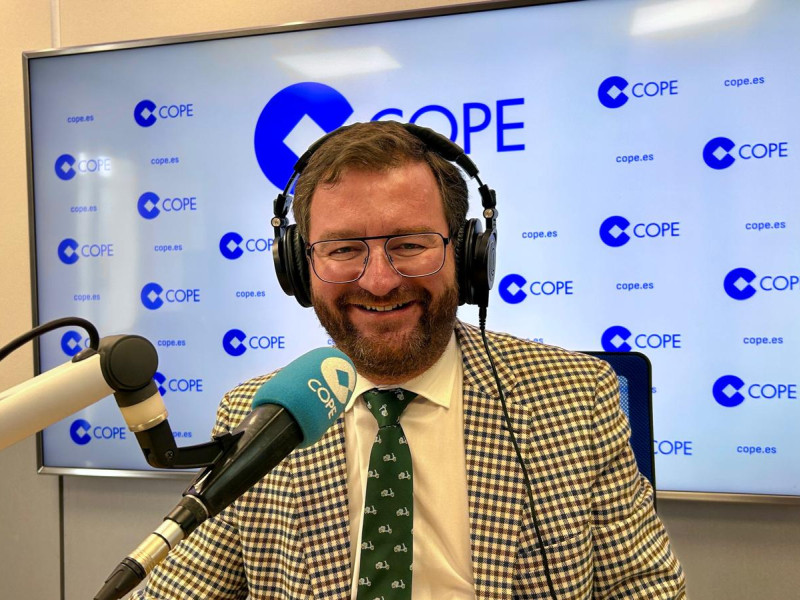 Antonio Martín en el estudio de COPE con los auriculares delante del micrófono y de fondo una pantalla con el logotipo de COPE