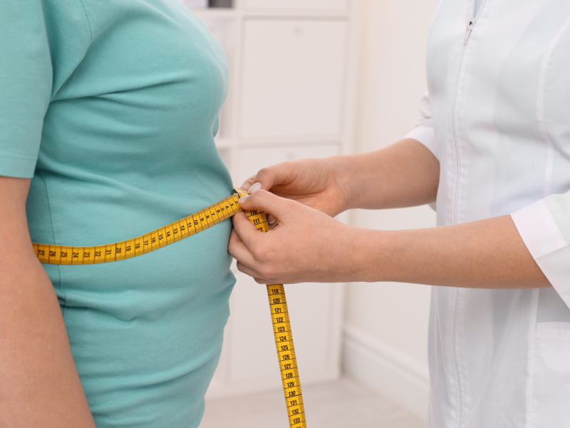 Una sanitaria tomando medidas a una persona con obesidad