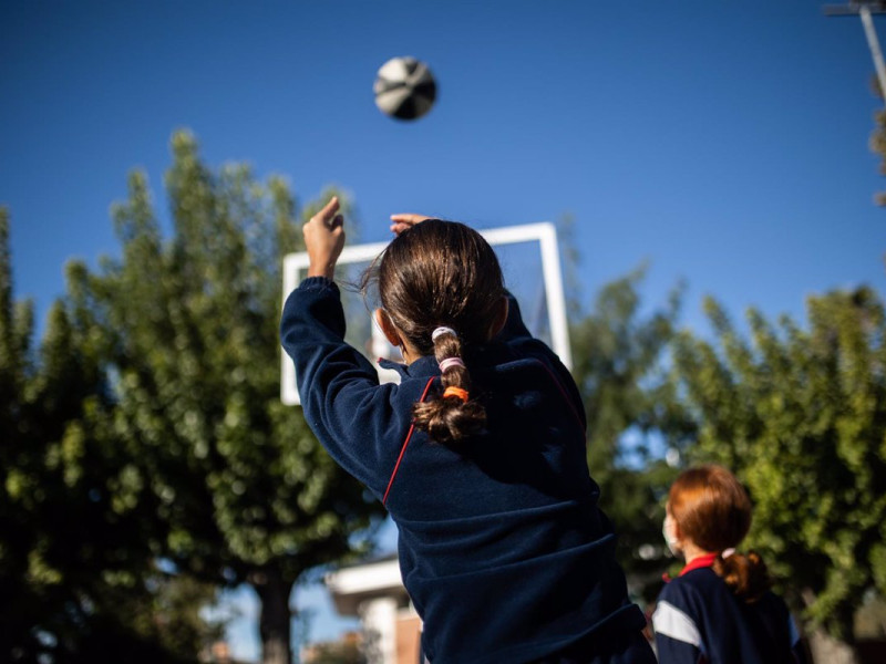 25-10-2021 Una niña juega al baloncesto en el patio del Colegio Alameda de Osuna el día en que entra en vigor la medida que permite no utilizar mascarilla en los patios escolares de Madrid, a 25 de octubre de 2021, en Madrid, (España). Con este permiso, que entra en vigor este lunes, Madrid se convierte en la primera comunidad autónoma que permite no llevar mascarilla en los patios de los colegios de la región, en los recreos y al aire libre, siempre y cuando se respete la distancia de seguridad interpersonal establecida por la pandemia. Esta medida, puesta en marcha por la Comunidad de Madrid, ha sido criticada por Sanidad, quien ha recordado que no se puede decidir unilateralmente la retirada de la mascarilla en los patios escolares ya que la ley en vigor desde el 29 de marzo establece el uso obligatorio en espacios al aire libre donde no sea posible mantener una distancia mínima de 1,5 metros.SOCIEDAD Alejandro Martínez Vélez - Europa Press