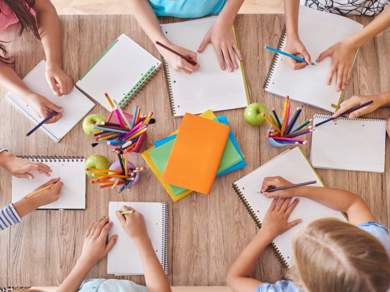 Niños en una escuela dibujando alrededor de una mesa