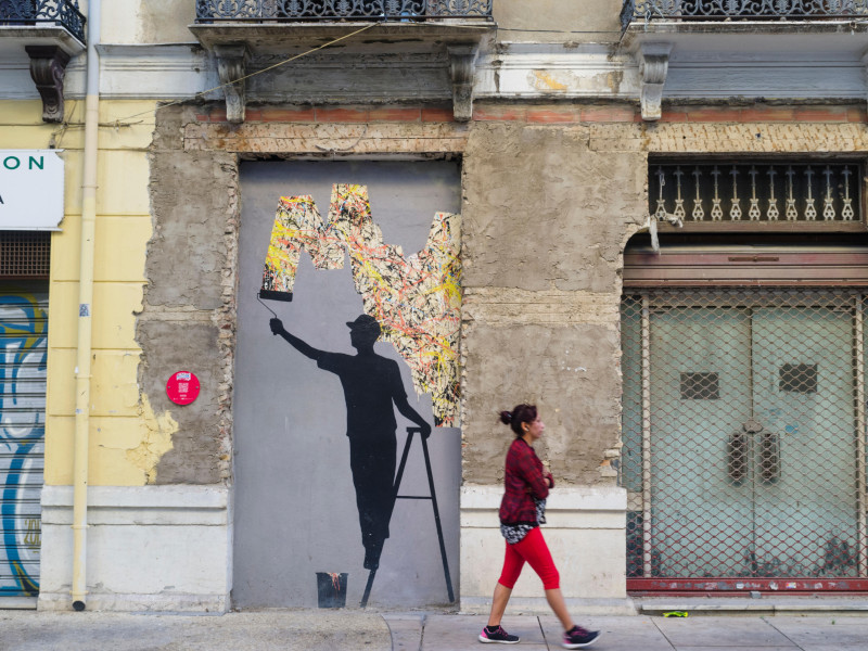 Una mujer pasa junto a un mural callejero del artista español Pejac en el bohemio barrio artístico del Soho en Málaga.