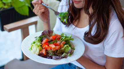 Chica comiendo un plato con verduras y salmón