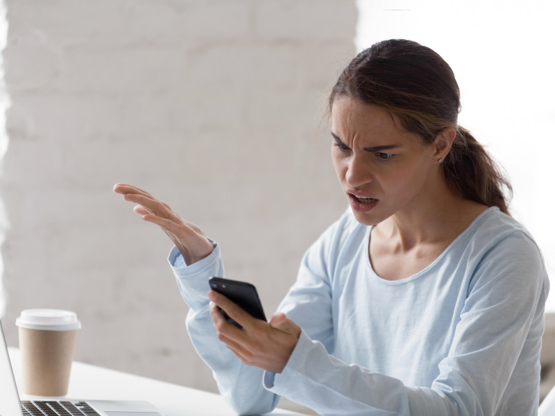 Mujer enojada y confundida que tiene problemas con el teléfono