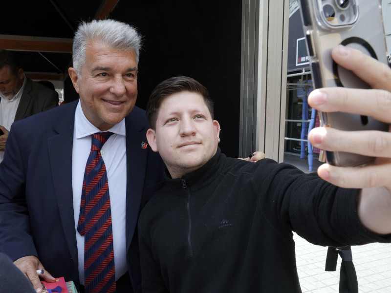 El presidente del FC Barcelona, Joan Laporta, se fotografía con un simpatizante en la carpa que el club ha instalado en el centro de Barcelona durante la Diada de Sant Jordi, en la que los catalanes toman las calles a la búsqueda de libros y rosas para regalar a sus seres queridos y allegados
