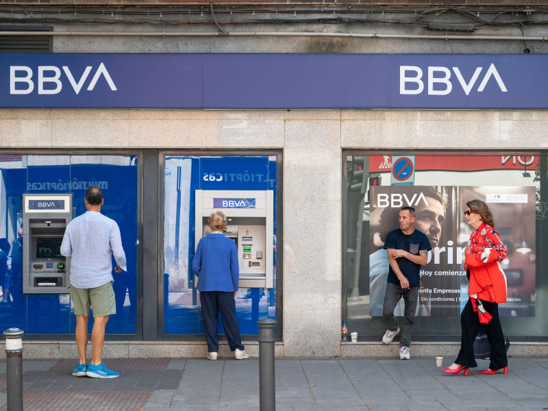 Un cliente retira dinero mientras otros hacen cola en un cajero automático del banco multinacional español Banco Bilbao Vizcaya Argentaria SA (BBVA) en España