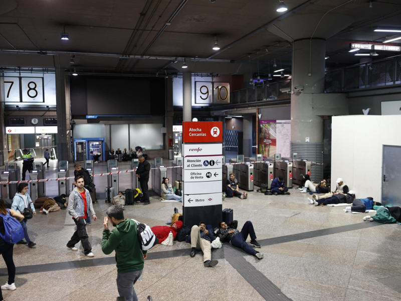Imagen de la estación de tren de Atocha, en Madrid, donde cientos de pasajeros esperan pasar la noche hasta que se reanude la circulación de trenes tras el apagón eléctrico que se ha producido hoy lunes en la Península Ibérica